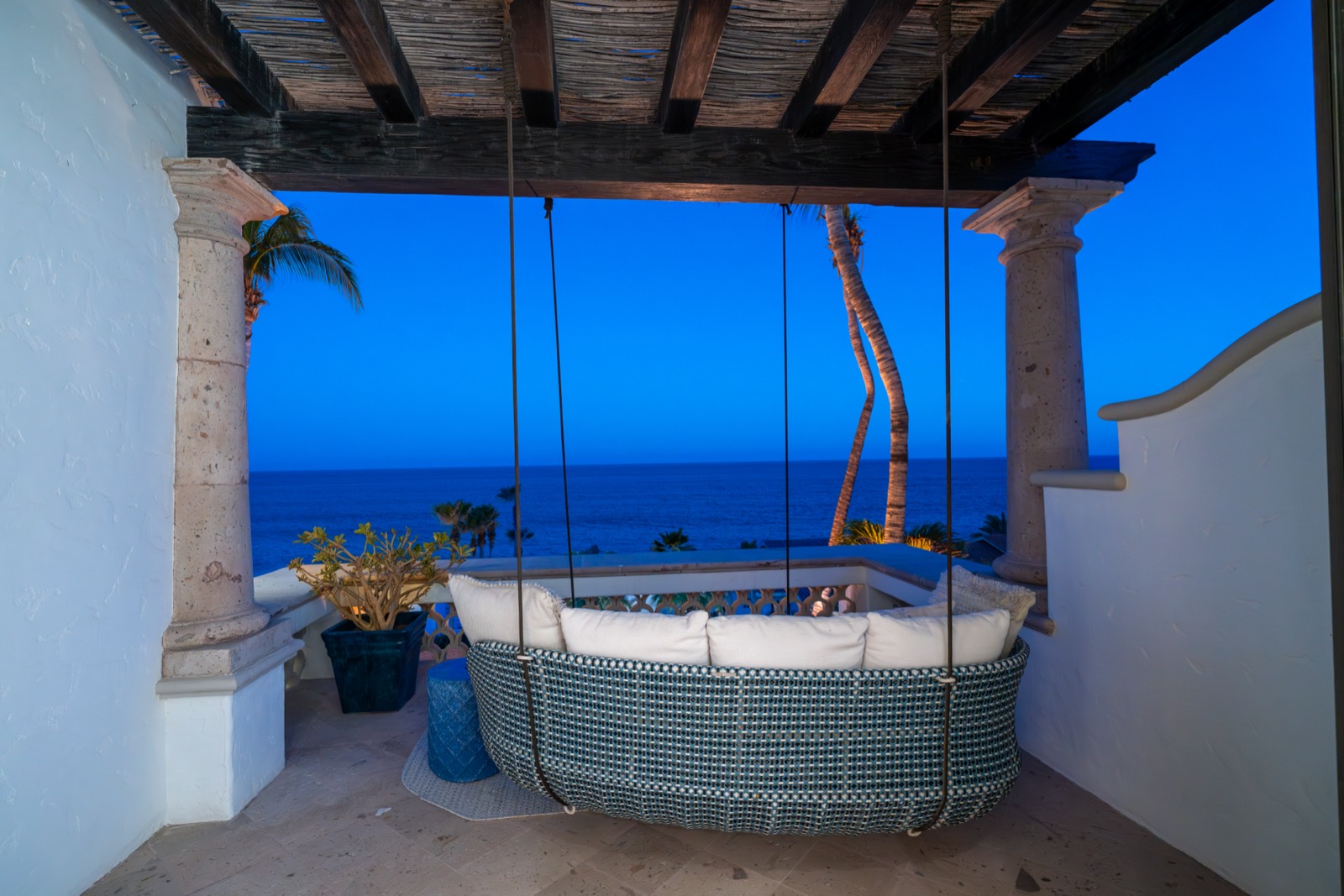 A hanging daybed on a private terrace overlooking the sea at blue hour