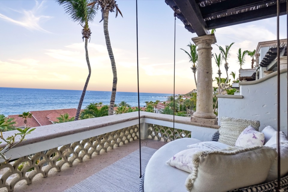 A terrace daybed at golden hour with the coastline and ocean beyond